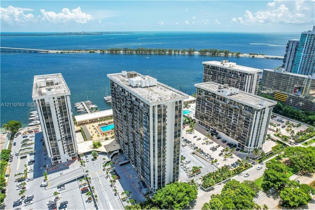High-rise residential complex featuring waterfront positioning, private surface parking, an outdoor swimming pool, and dedicated boat slips