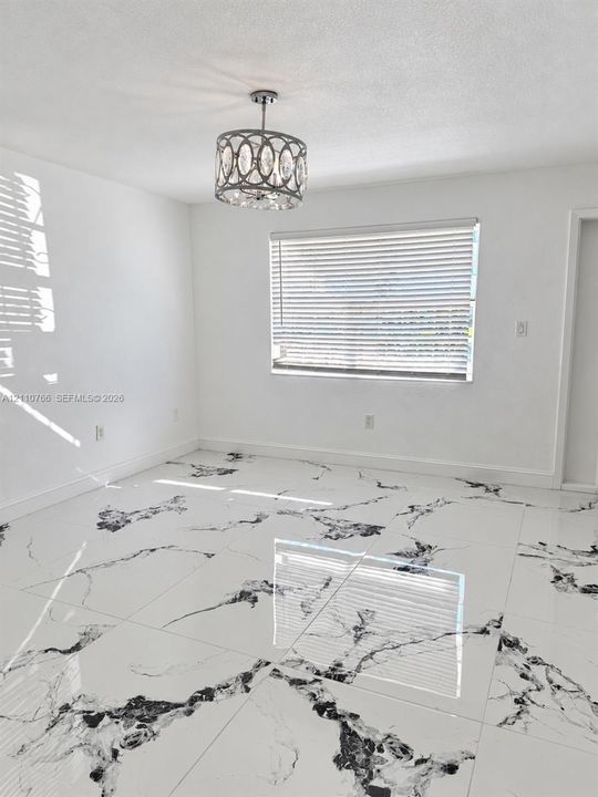 Large-format white tile flooring with black veining, polished finish, and a central drum-style chandelier with crystal accents and horizontal window blinds