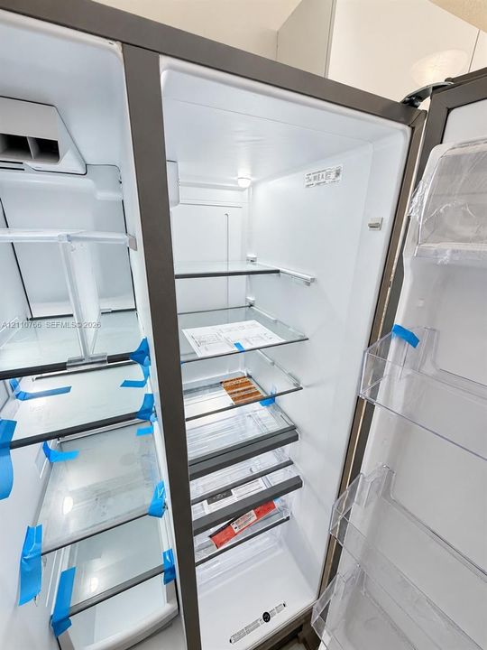 Side-by-side refrigerator featuring adjustable glass shelving, clear polycarbonate door bins, and integrated interior lighting
