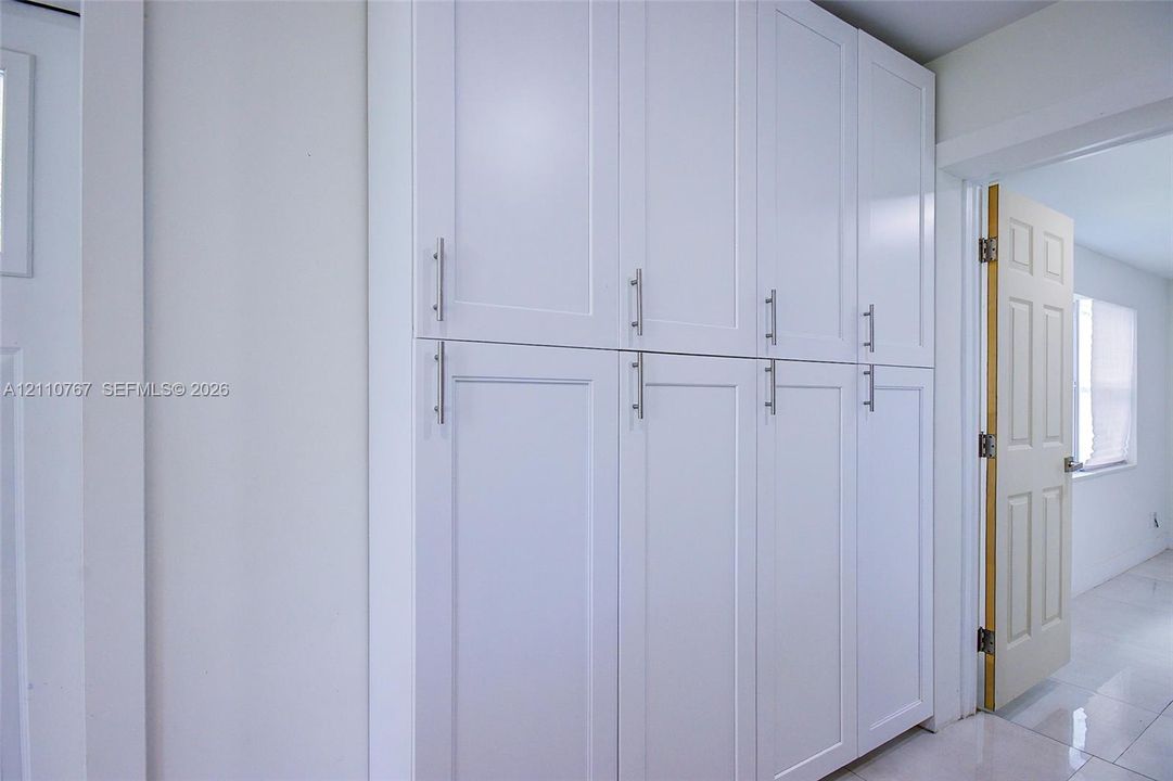 Built-in floor-to-ceiling cabinetry featuring white Shaker-style doors and metallic bar pulls