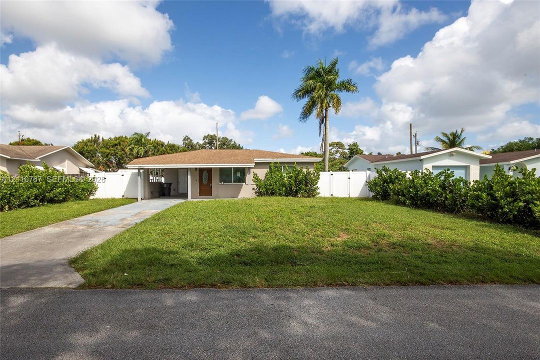 Single-story residence featuring a low-slope roof, covered entryway, concrete driveway, and full-perimeter vinyl privacy fencing