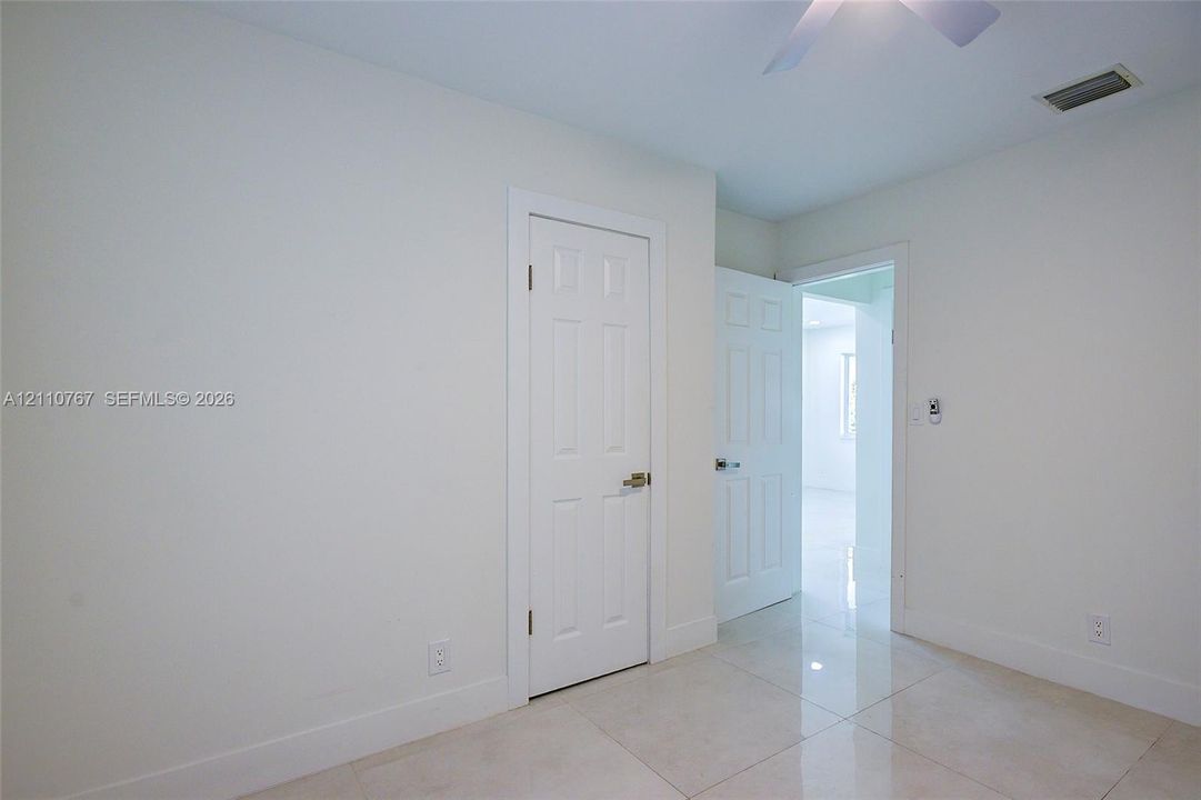 Polished tile flooring, six-panel interior doors, and a ceiling-mounted fan fixture