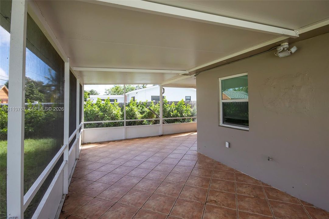 Screened-in patio featuring a solid roof covering, diamond-patterned tile flooring, and perimeter screening