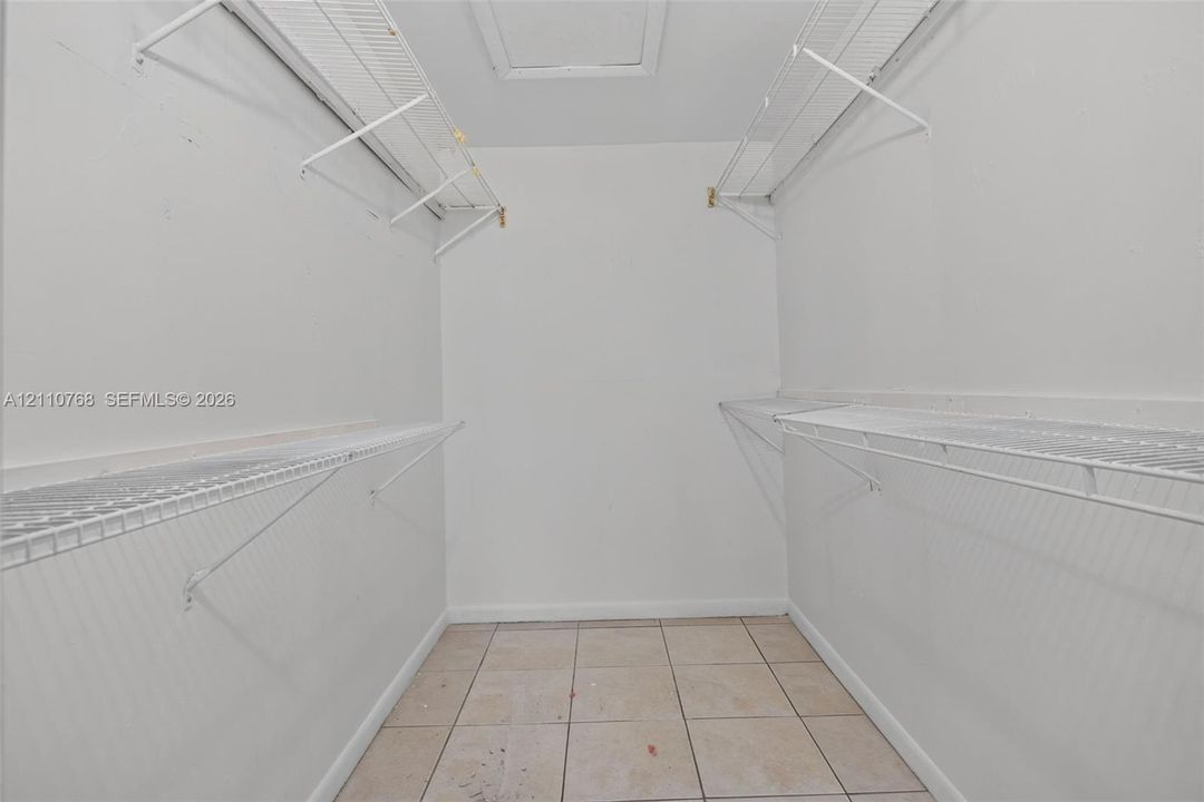 Walk-in storage space featuring ceramic tile flooring and multi-level white wire shelving