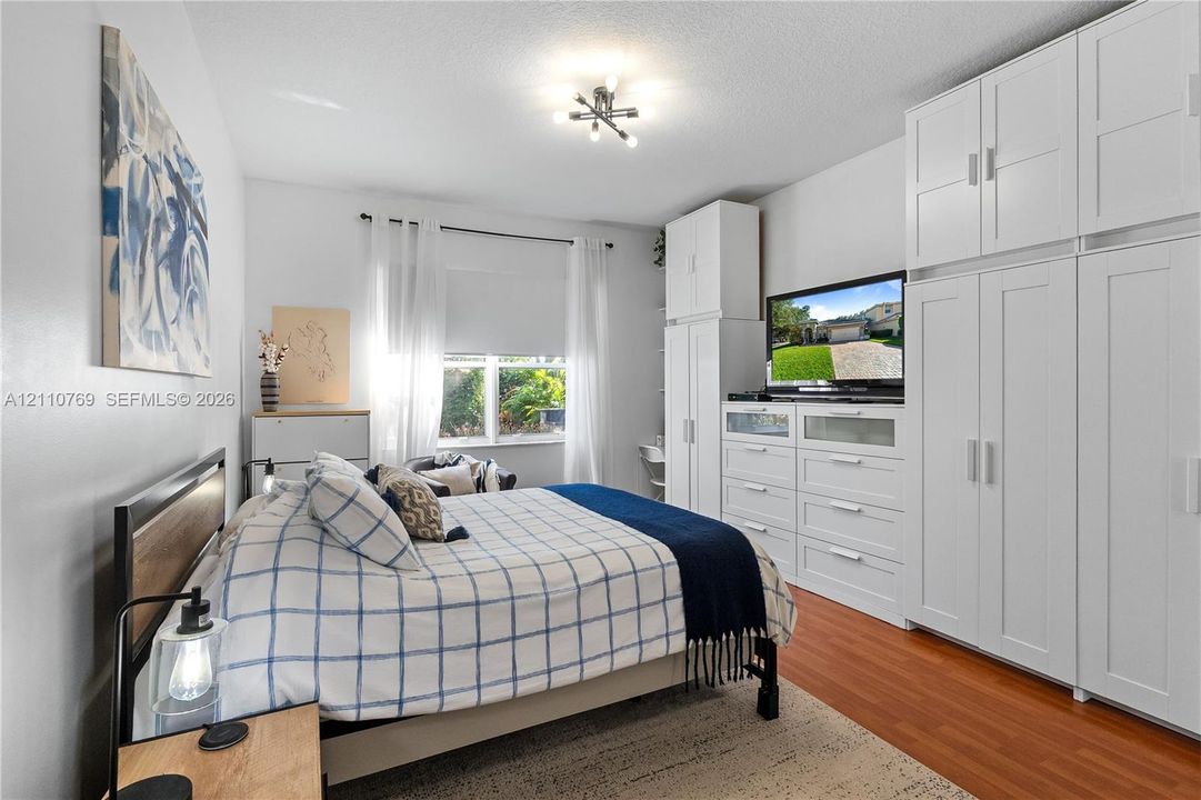 Custom floor-to-ceiling white cabinetry with integrated media storage and multi-light brushed metal ceiling fixture