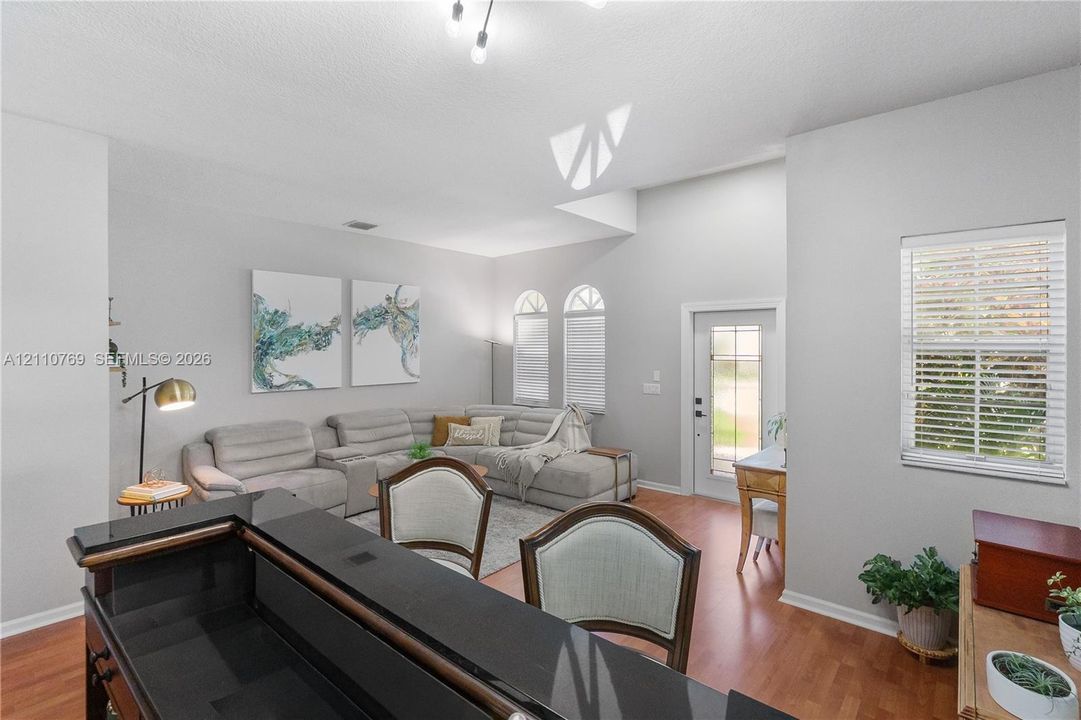 Open-concept living space featuring vaulted ceilings, wood-finish flooring, arched windows, and a built-in counter with a stone surface