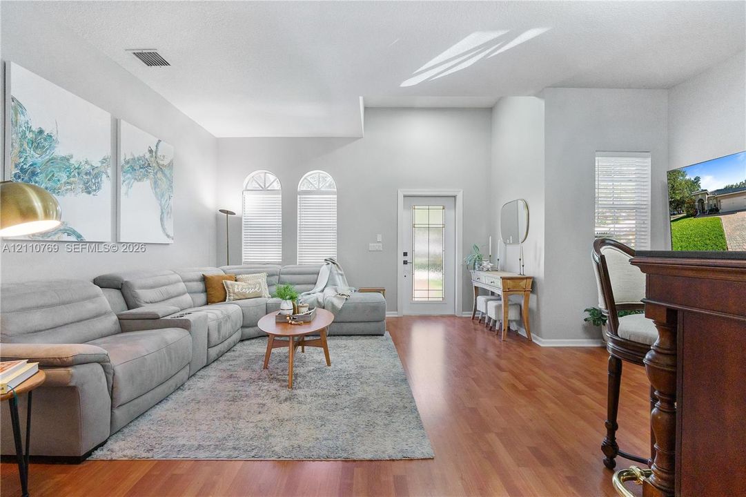 Living area featuring vaulted ceilings, wood-finish flooring, and arched windows