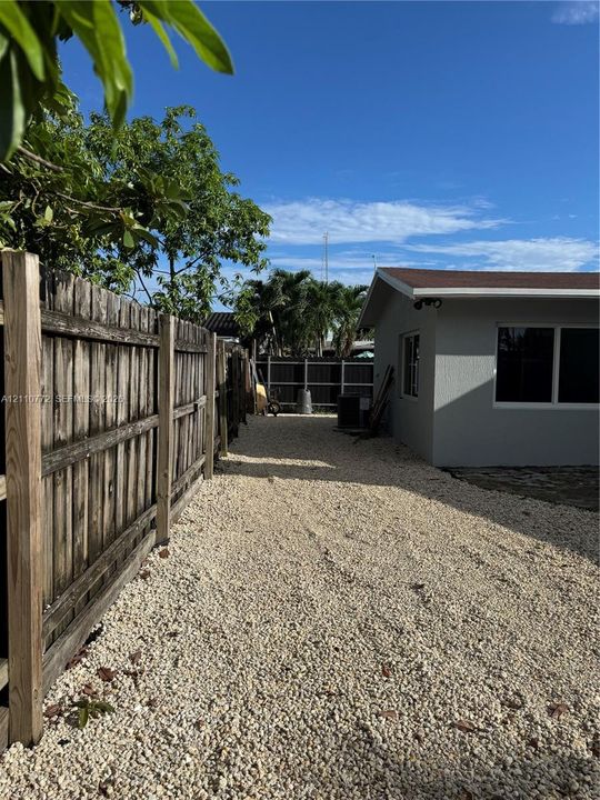 Side yard featuring a crushed stone surface and a wood perimeter fence