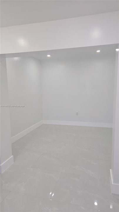 Neutral-toned large-format tile flooring, recessed ceiling lighting, and smooth finished walls