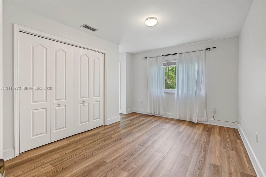 Room featuring wood-finish flooring, four-panel closet doors, and flush-mount lighting