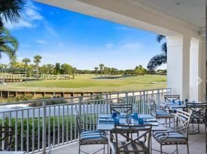 Covered balcony featuring tile flooring, structural columns, and metal railing overlooking a golf course