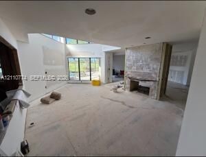 Open-concept interior featuring a floor-to-ceiling fireplace with stone-finish surround, multi-panel sliding glass doors, and recessed lighting