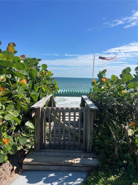 Private wooden beach access gate with a path leading to a timber pergola overlooking the ocean