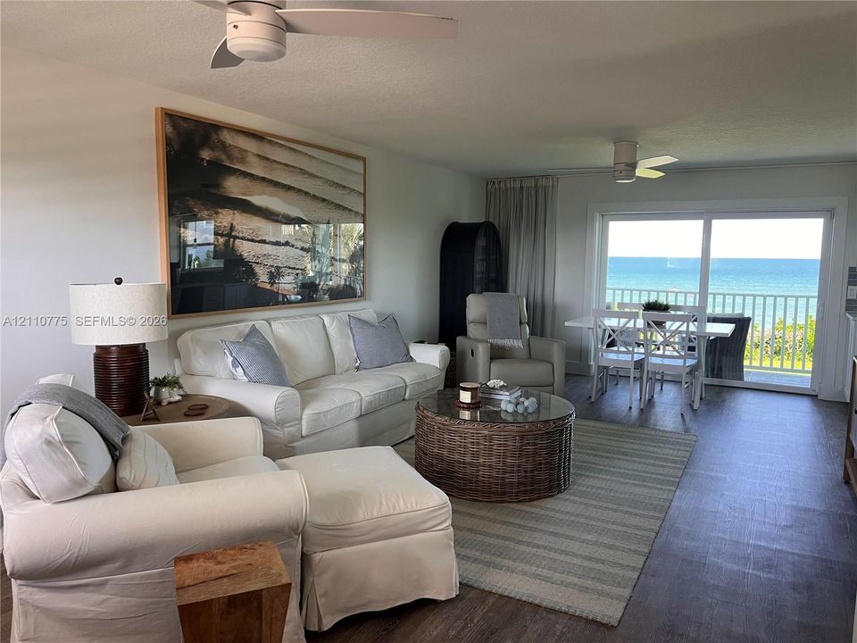 Living area featuring wood-finish flooring, white ceiling fans, and sliding glass doors with direct access to an exterior balcony