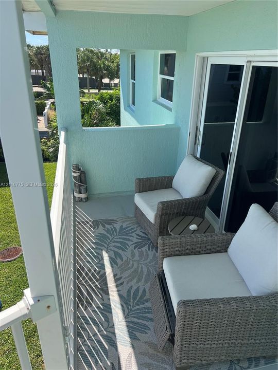 Private balcony featuring stucco walls, a metal railing, and sliding glass door access