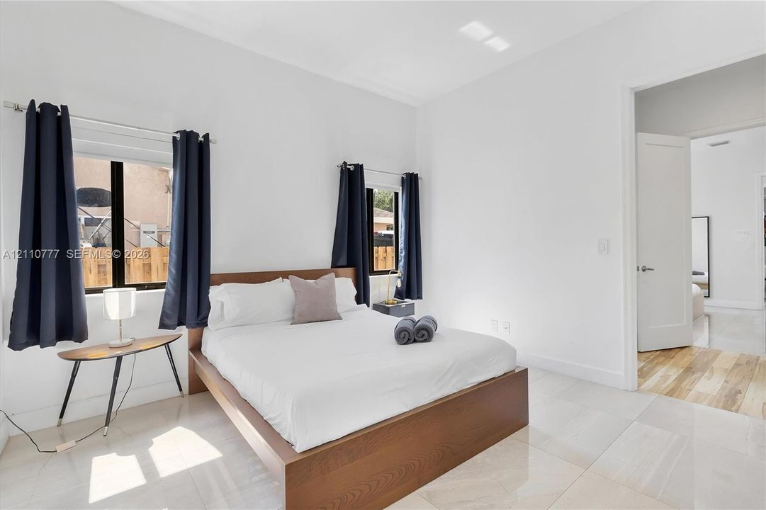 Large-format tile flooring, neutral wall tones, and two windows with black-finish window frames and hardware