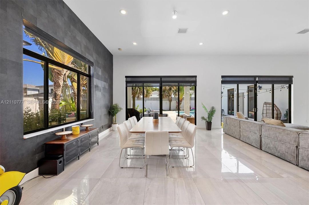 Spacious interior featuring large-format tile flooring, a charcoal-toned textured accent wall, recessed lighting, and multiple sliding glass door systems
