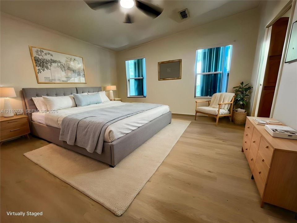Spacious room featuring wood-finish flooring, dual windows, and an attached ceiling fan
