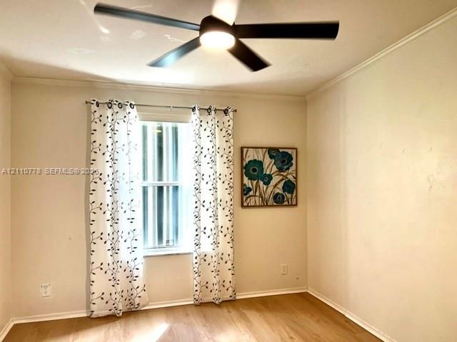 Wood-finish flooring, matte black ceiling fan with integrated lighting, and single-pane window