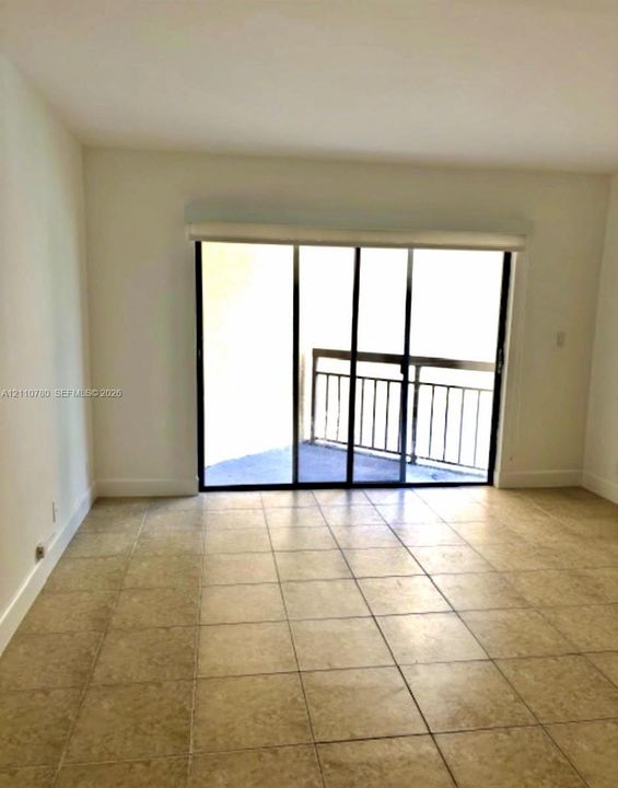 Neutral-toned tile flooring, oversized glass sliding doors, and a private balcony featuring metal railings