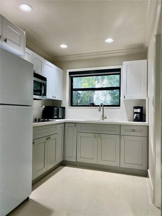 Kitchen featuring white shaker-style upper cabinets, light gray lower cabinetry, recessed lighting, solid surface countertops, and a stainless steel undermount sink