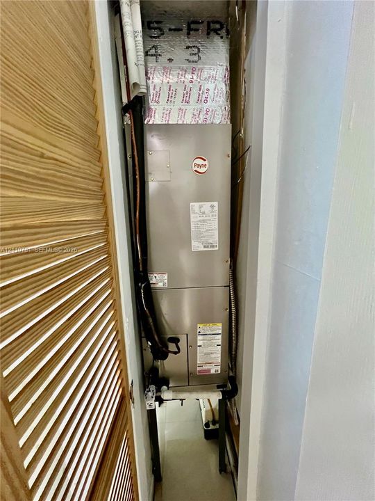 Payne HVAC air handler unit enclosed within a dedicated utility closet featuring wood-finish louvered doors