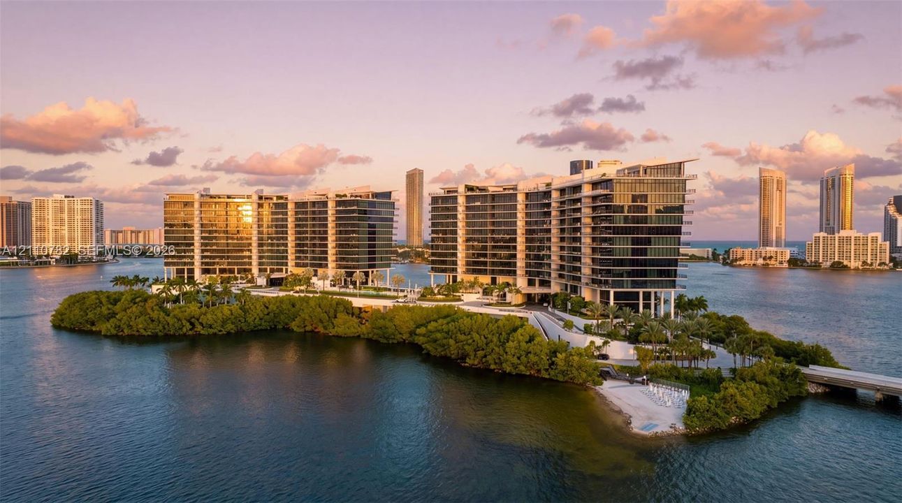 Waterfront residential complex featuring floor-to-ceiling glass facades, wraparound balconies, professional landscaping, and private island access