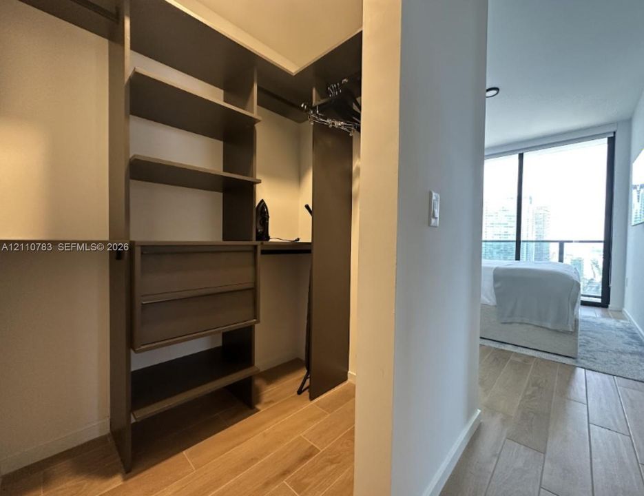 Custom walk-in closet featuring floor-to-ceiling built-in shelving, integrated drawers, and wood-finish flooring