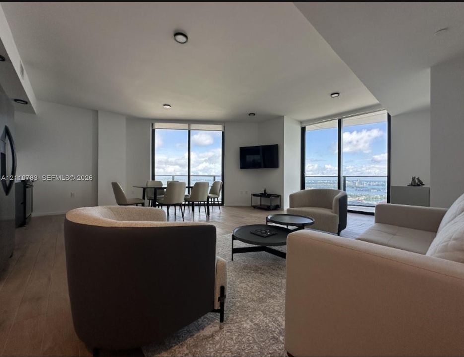 Open-concept interior featuring floor-to-ceiling windows, wood-finish flooring, recessed lighting, and balcony access