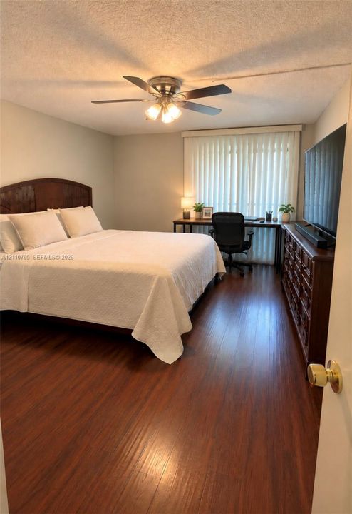 Wood-finish flooring, ceiling fan with integrated lighting, and vertical window blinds