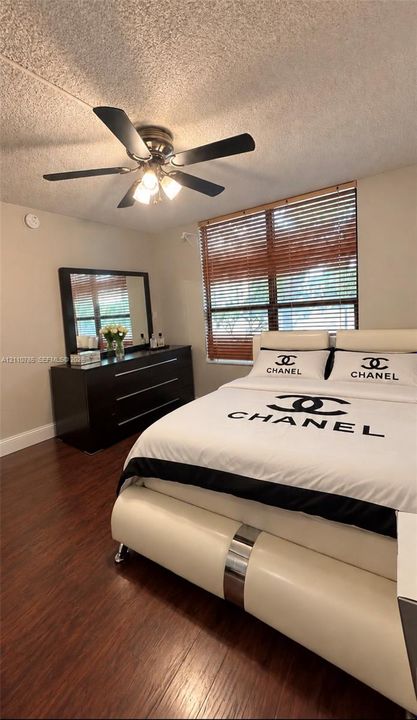 Wood-finish flooring, multi-blade ceiling fan with integrated lighting, and horizontal window blinds