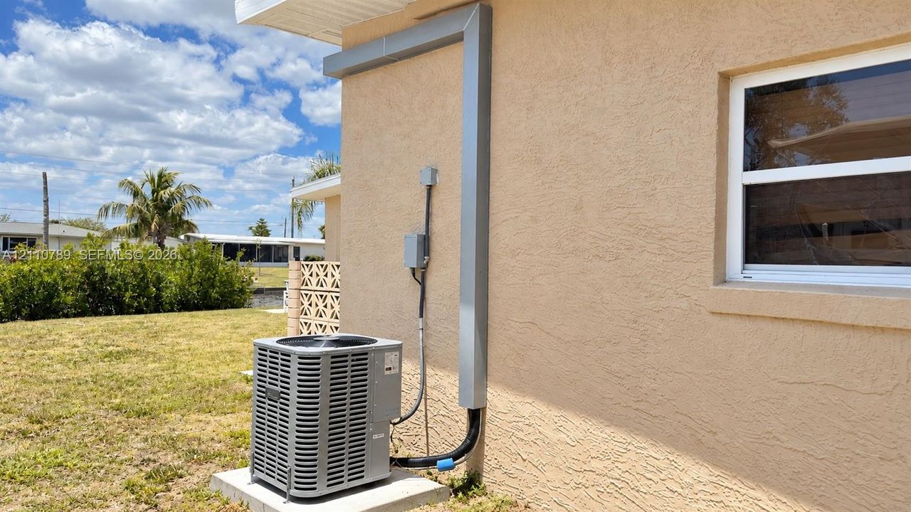 Exterior stucco siding, single-hung window, and installed outdoor HVAC unit