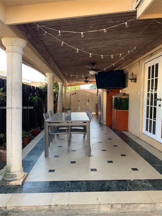 Covered patio featuring decorative columns, a wood-finish ceiling, and tile flooring with a patterned inlay