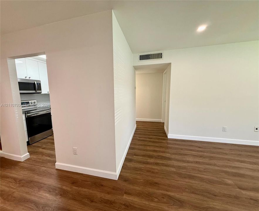 Wood-finish flooring throughout, stainless steel range and microwave, and white cabinetry