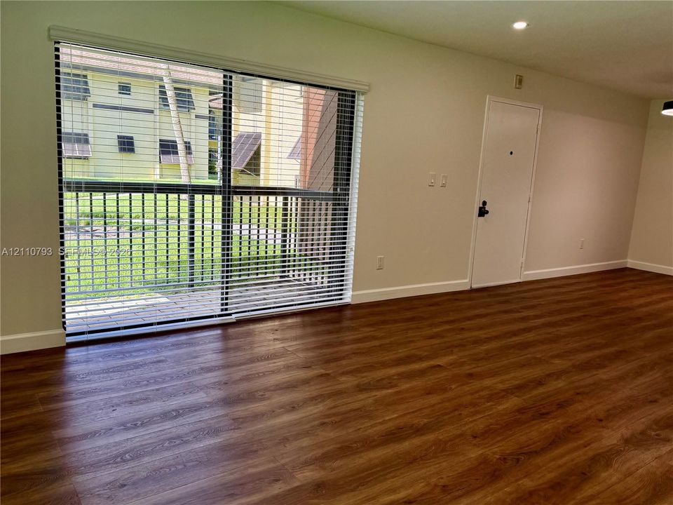 Interior space featuring wood-finish flooring, large sliding glass doors, horizontal blinds, and a recessed ceiling light fixture