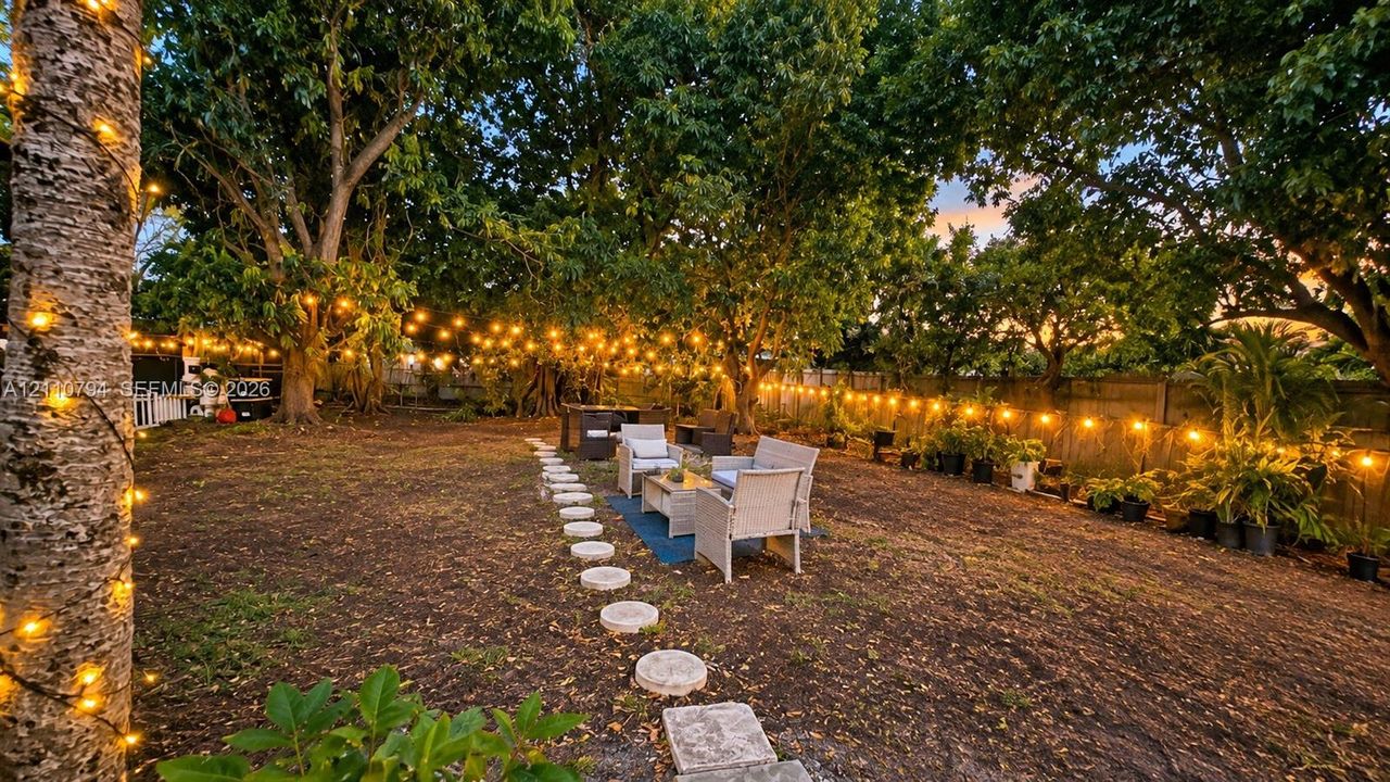 Private backyard featuring mature trees, a stone paver path, and perimeter fencing