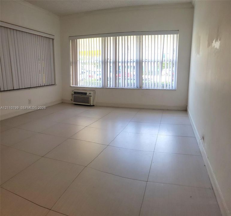 Large-format ceramic floor tiling, multiple expansive windows with integrated vertical blinds, and a wall-mounted air conditioning unit