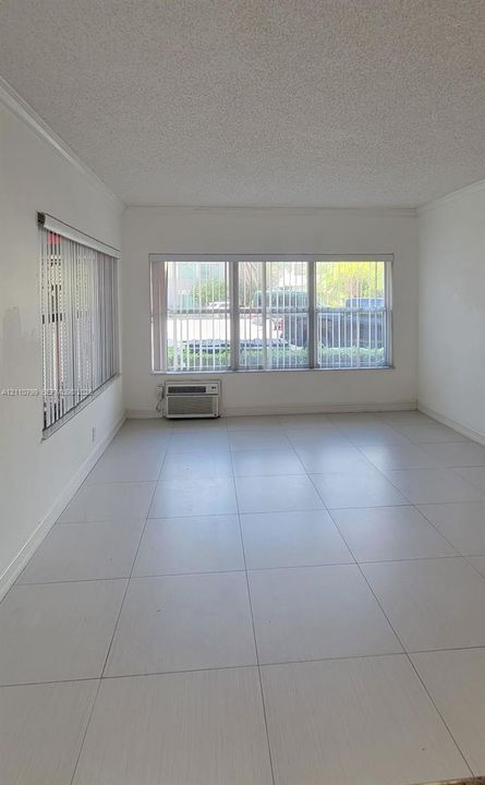 Light-filled room featuring neutral large-format tile flooring, textured ceilings, and expansive multi-pane windows with vertical blinds