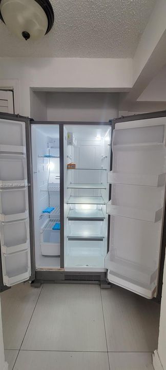 Stainless steel side-by-side refrigerator featuring adjustable glass shelving, clear storage drawers, and integrated door bins