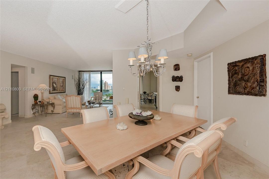 Dining area featuring stone-finish tile flooring, a multi-arm decorative chandelier, and a vaulted ceiling