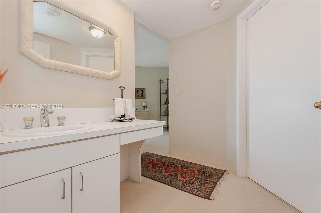 Built-in white cabinetry with a surface-mounted vanity sink, polished chrome faucet, and framed wall mirror