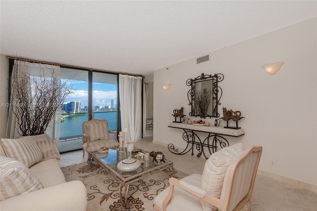 Floor-to-ceiling sliding glass doors, neutral stone-finish tile flooring, and wall-mounted sconce lighting