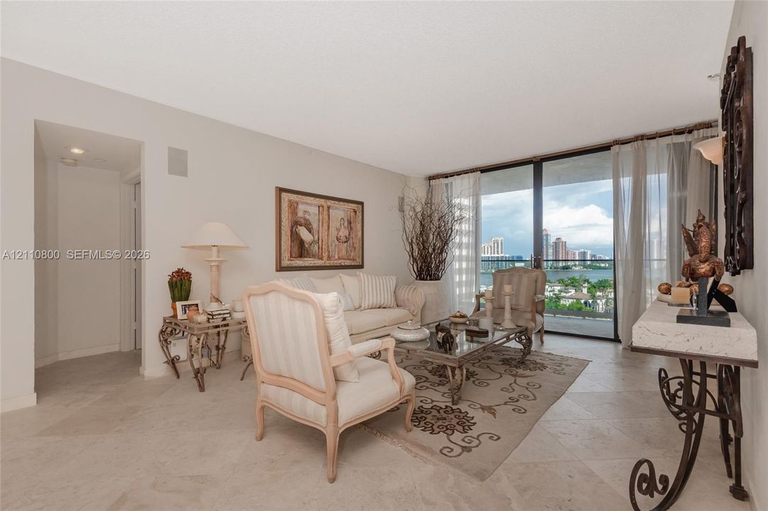 Living area featuring large-format tile flooring and floor-to-ceiling glass sliding doors opening to a balcony