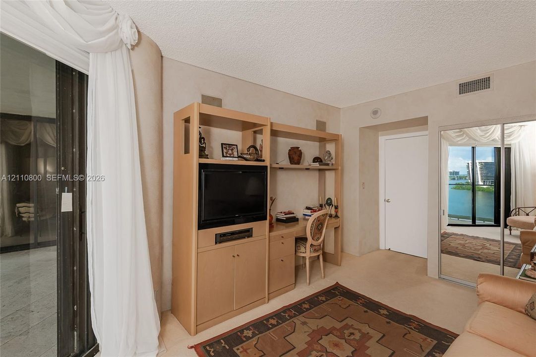 Built-in wood cabinetry with integrated desk space, sliding glass doors, mirrored closet doors, and water scenery
