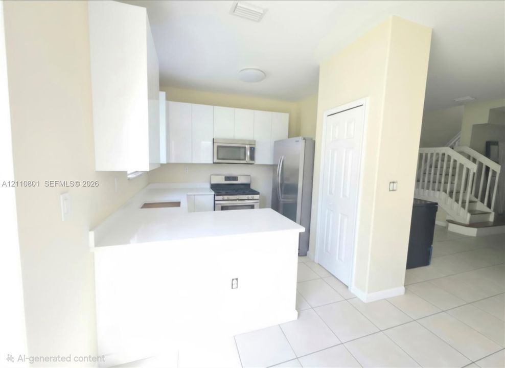 Kitchen featuring white flat-panel cabinetry, light-toned stone countertops, stainless steel appliances, and large-format tile flooring