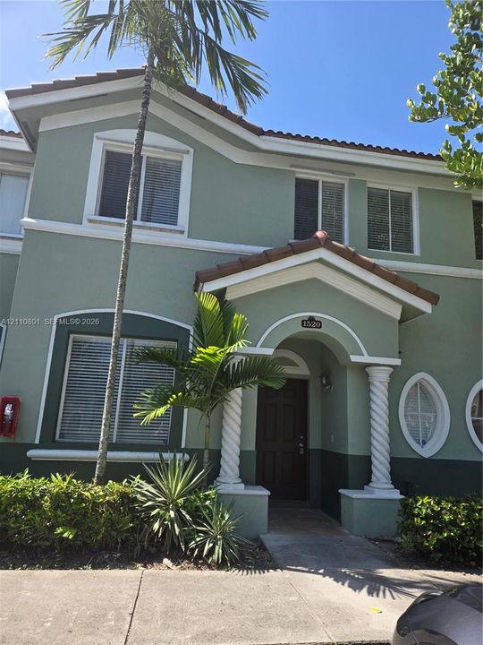 Two-story exterior featuring a stucco façade, tiled roof, decorative spiral columns, and oval-shaped accent windows