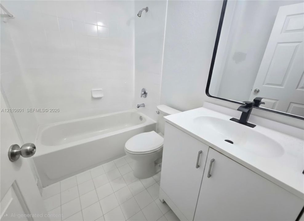 Bathroom featuring a white vanity with a composite countertop, matte black faucet, rectangular mirror with a black frame, and a white tiled shower-tub combination