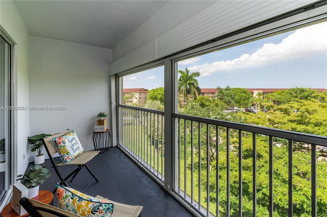 Enclosed balcony featuring floor-to-ceiling windows, metal railing, and solid flooring