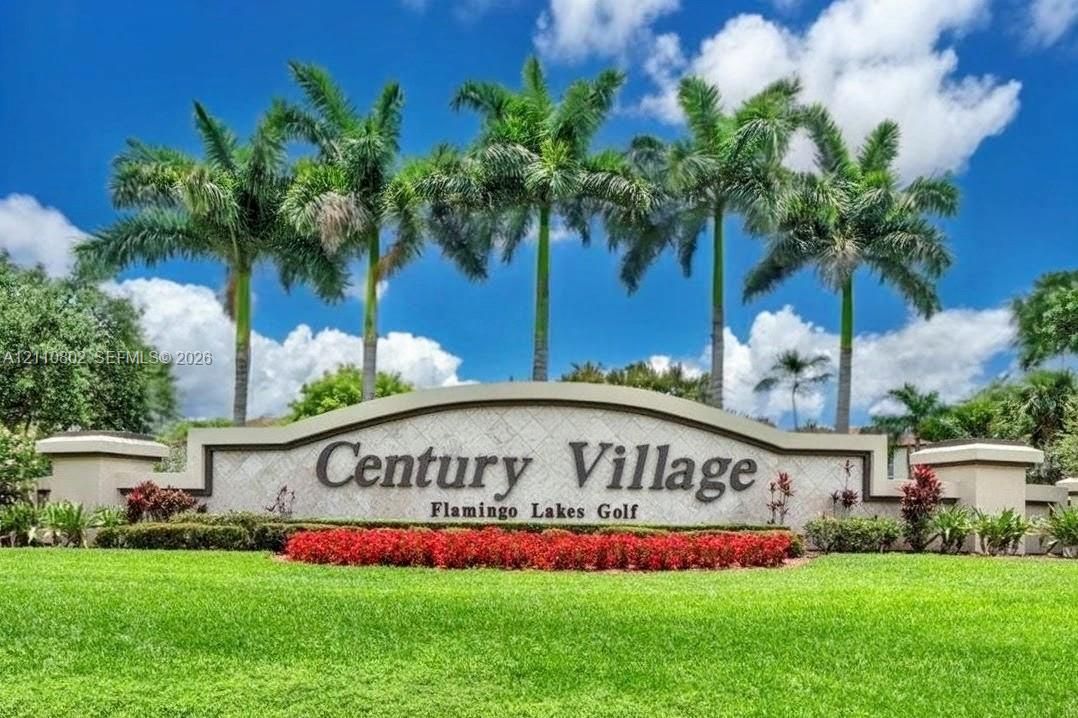 Century Village community entrance monument featuring stone-texture detailing, mature palm trees, and manicured landscaping