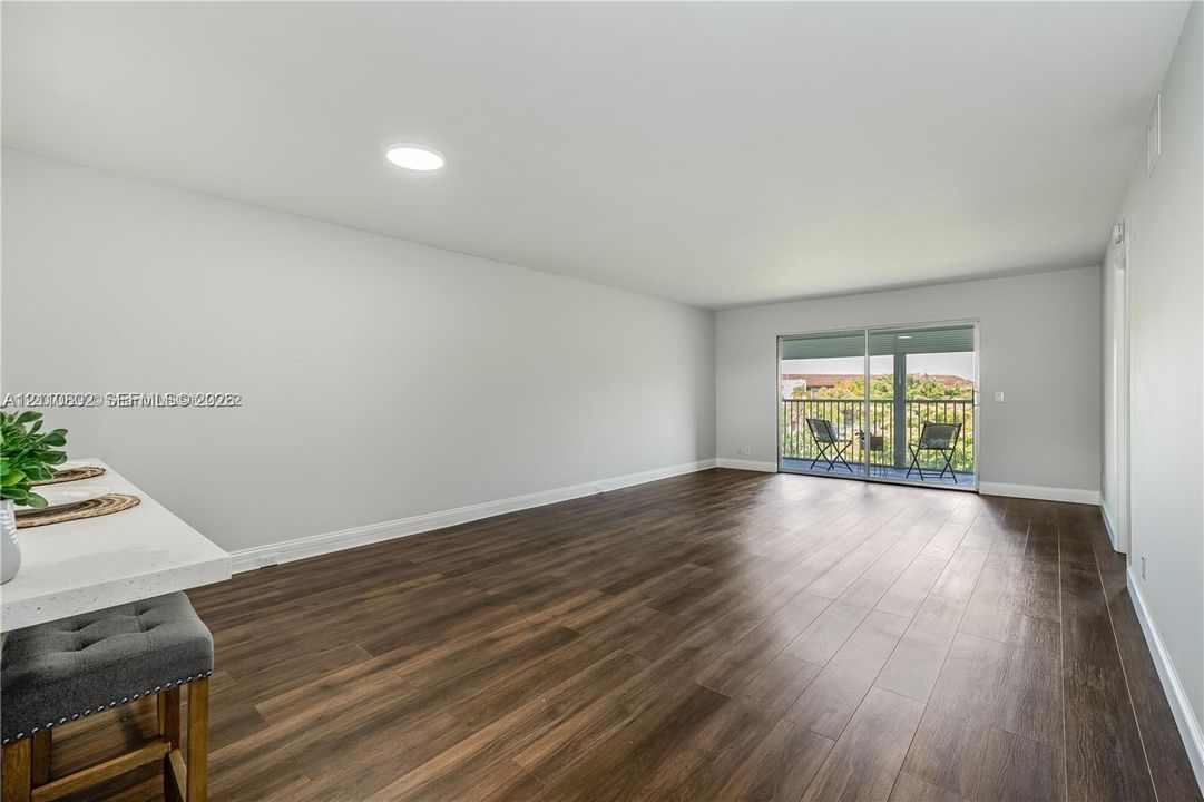 Open-concept living space featuring wood-finish flooring, recessed lighting, and sliding glass doors with exterior access